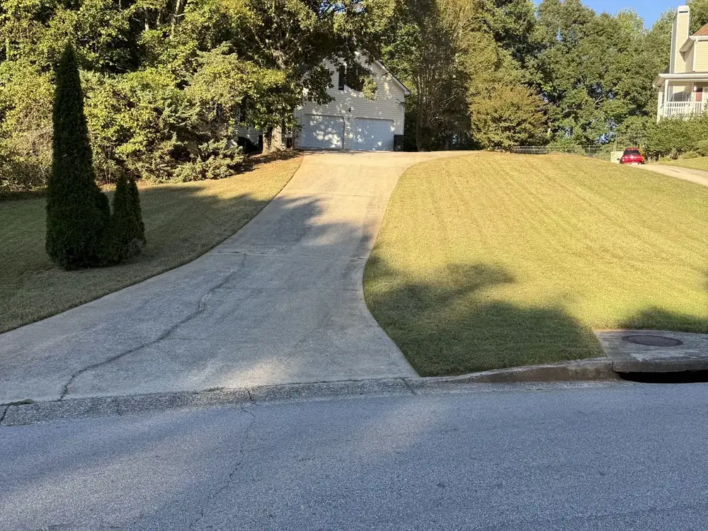 Sloped front lawn mowed in stripes beside a driveway in Douglasville, GA